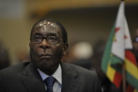 Arlywydd Zimbabwe wrth ddesg, a baner ei wlad y tu ol iddo